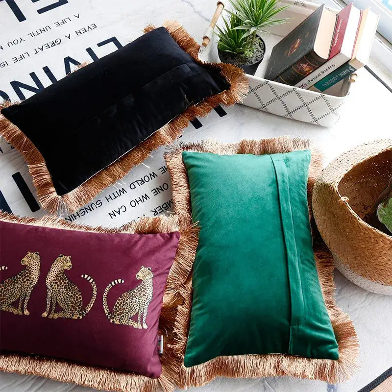 Three velvet throw pillow covers in black emerald green and burgundy with gold leopard print and tassel fringe edges