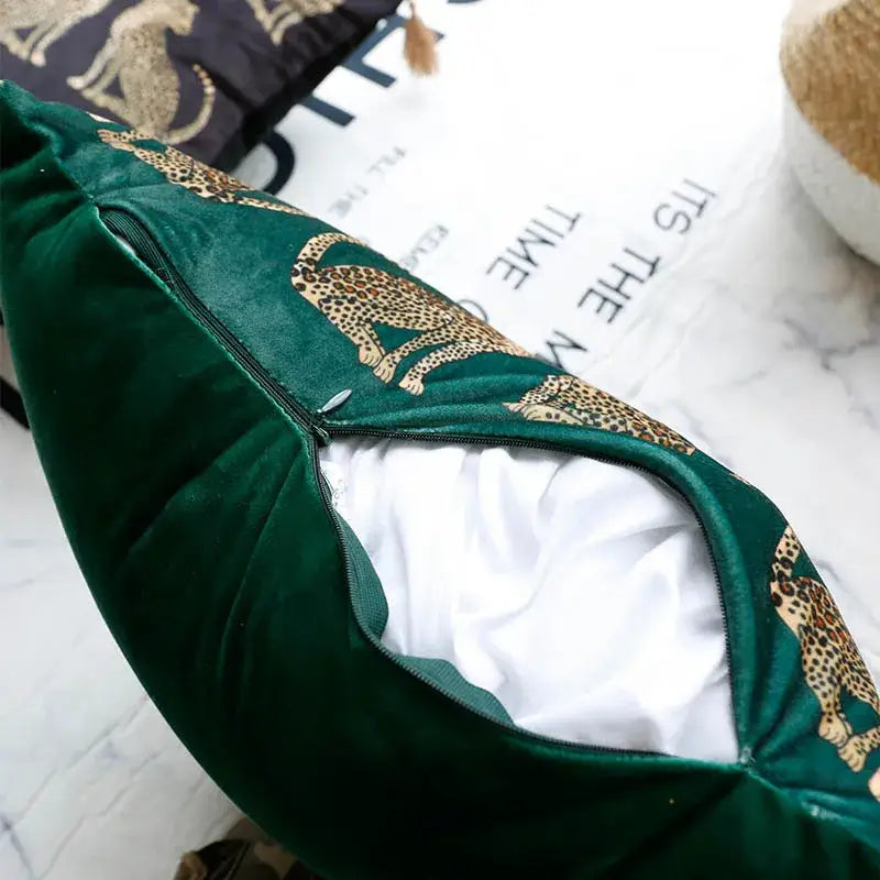 Emerald green velvet throw pillow cover with gold leopard print zipper opening revealing white interior lining
