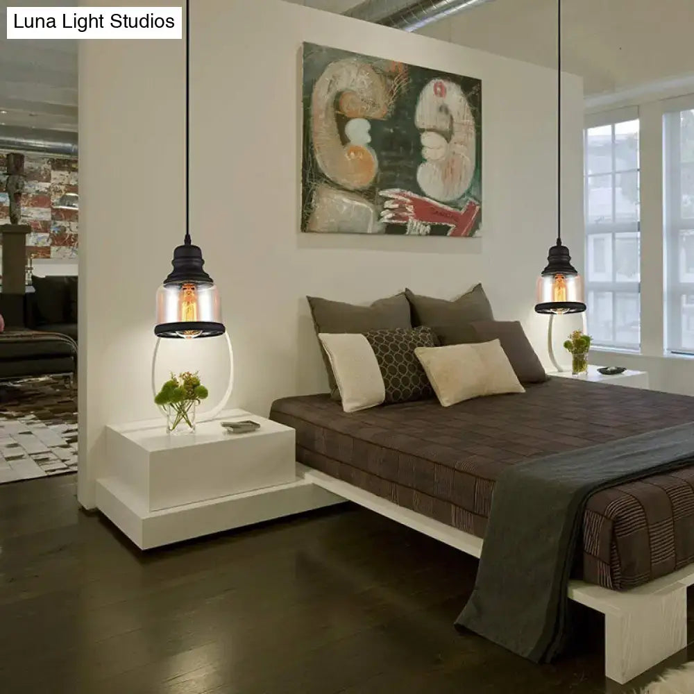 Black industrial cylinder pendant lighting with clear glass shades and exposed bulbs hanging above a living room bed