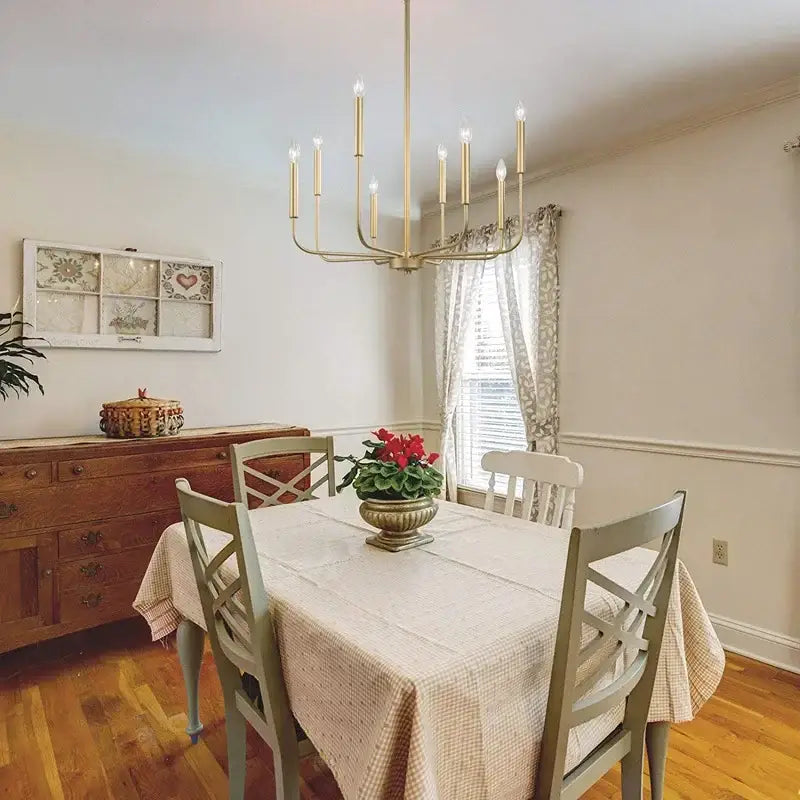 A gold-toned decorbites iron branch chandelier pendant light with candle-style bulbs hanging above a dining table