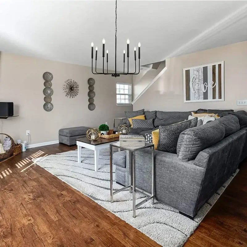 Gray sectional sofa with patterned pillows under black decorbites iron branch chandelier pendant light in dining room