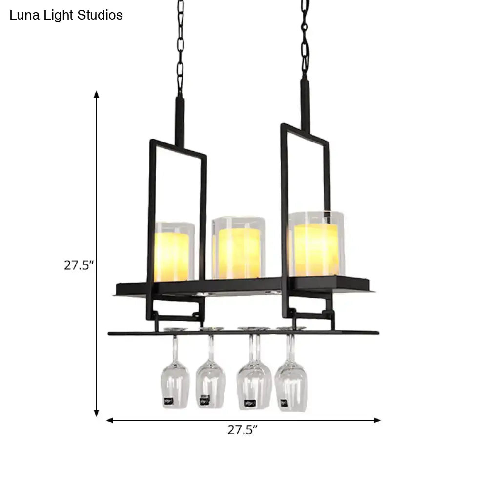 Black metal island light fixture with three glowing yellow candle-style lights and clear glass cylindrical wine glass rack