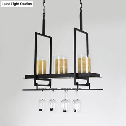 Decorbites black metal wine rack with glass candle holders and hanging wine glasses beneath clear glass cylindrical island light fixture