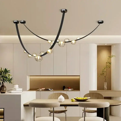 Modern black metal pendant light with curved arms and clear glass globe light sources as dining room focal point