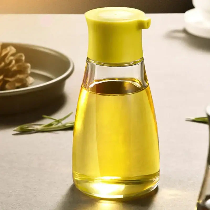 Clear glass 170ml seasoning bottle with bright yellow pump lid filled with golden soy sauce or cooking oil