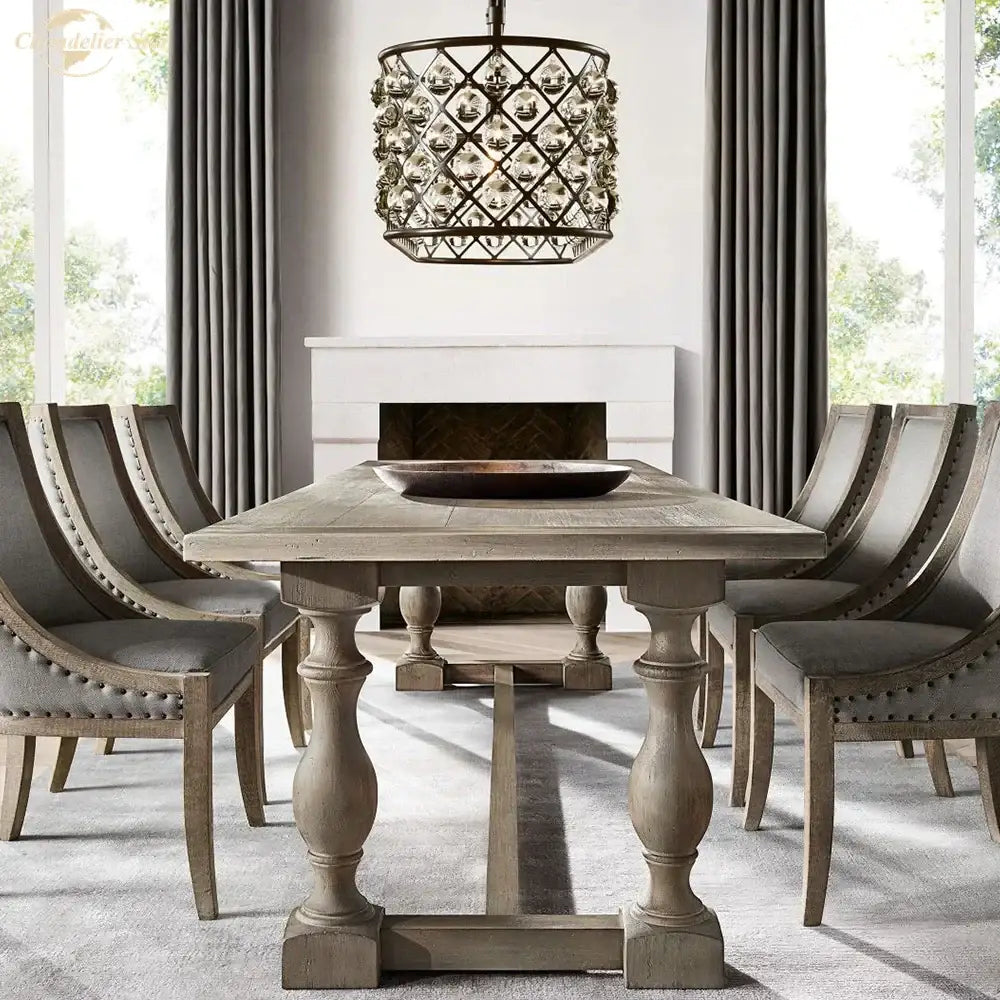 Black metal glass drop chandelier pendant lights hanging above gray distressed wood dining table with turned legs