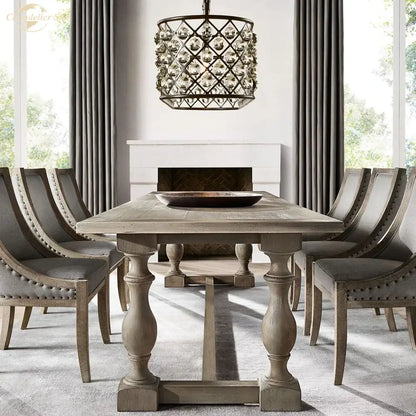 Black metal glass drop chandelier pendant lights hanging above gray distressed wood dining table with turned legs