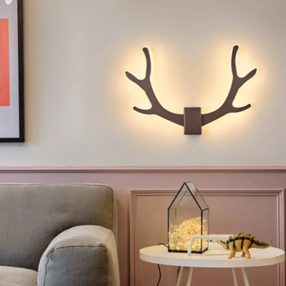 Dark brown metallic antler sconce wall mounted lighting fixture with warm glowing light for bedroom use