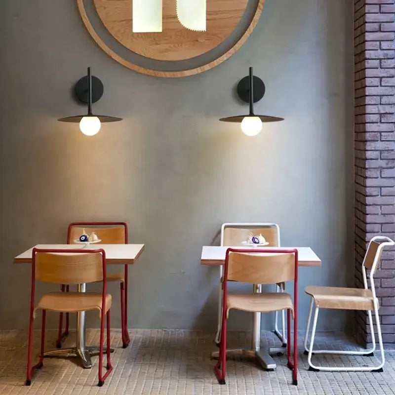 Red metal-framed chairs with light wood seats complement black minimalist glass ball wall lamp bedroom sconce decorbites glass ball wall