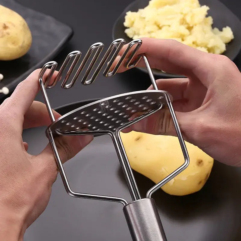Black and silver stainless steel potato masher with perforated flat base and curved ridged pressing head for kitchen use
