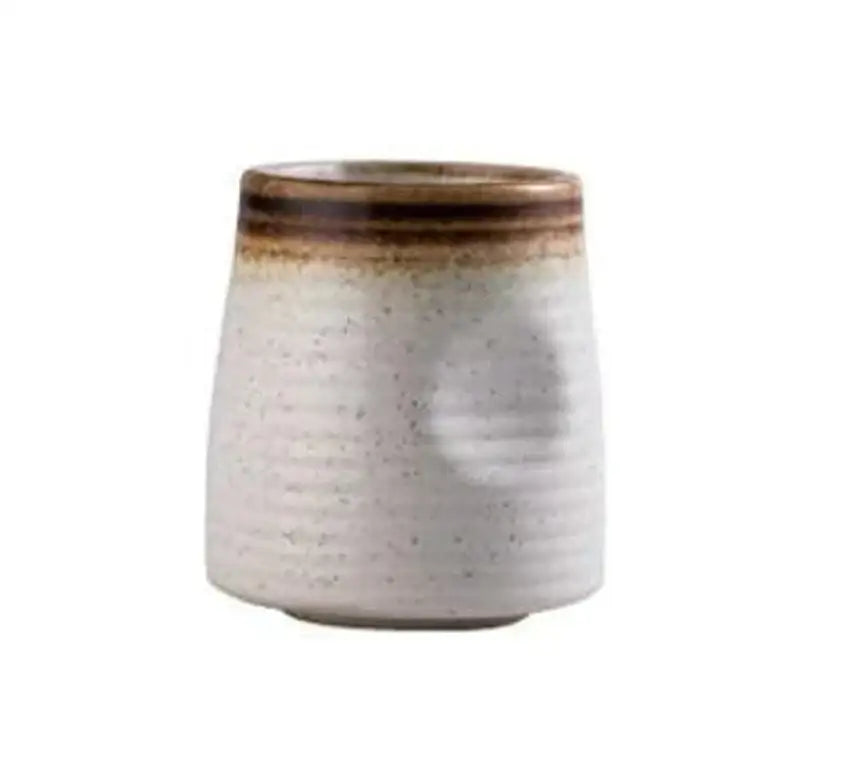A rustic white ceramic wine sake tumbler with textured ribbed surface and brown glazed rim in a ceramic wine sake set