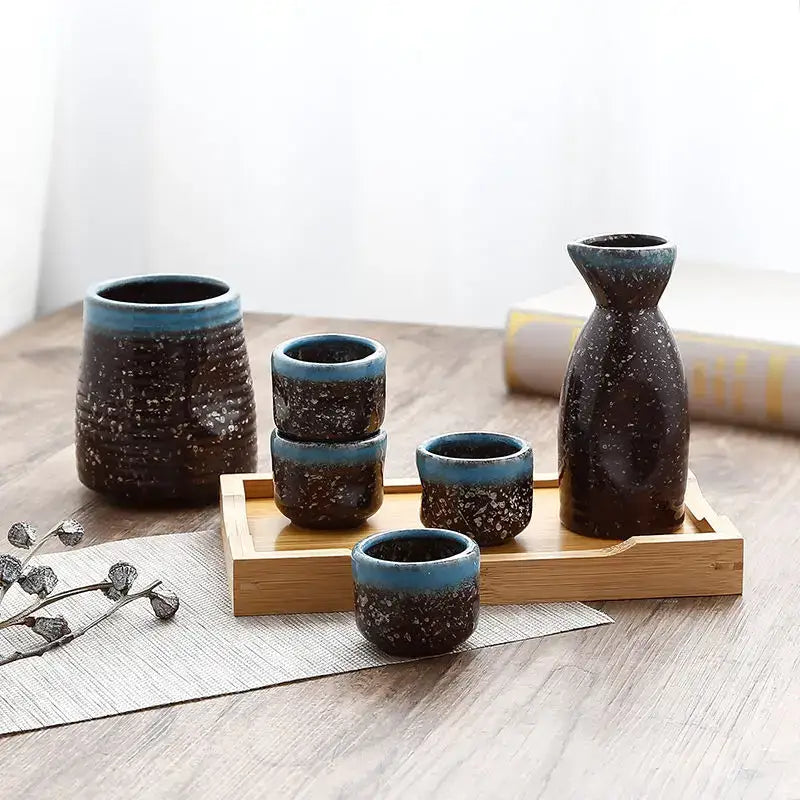 Black speckled ceramic wine sake set with heater featuring tall bottle, cylindrical container, and cups on wooden tray decorbites ceramic wine