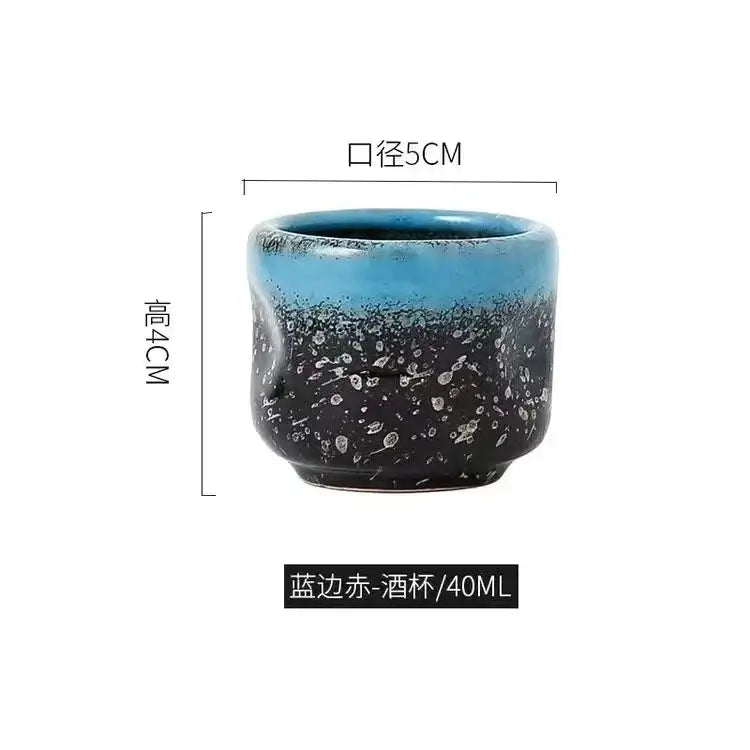 A ceramic wine sake cup with gradient blue black glaze and white speckles in a black speckled ceramic wine sake set