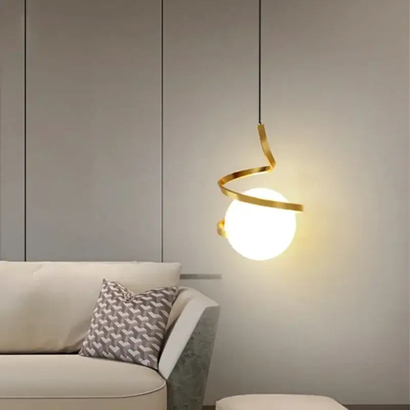 A black spiral cord pendant light with golden metal frame and white globe for modern kitchen installation