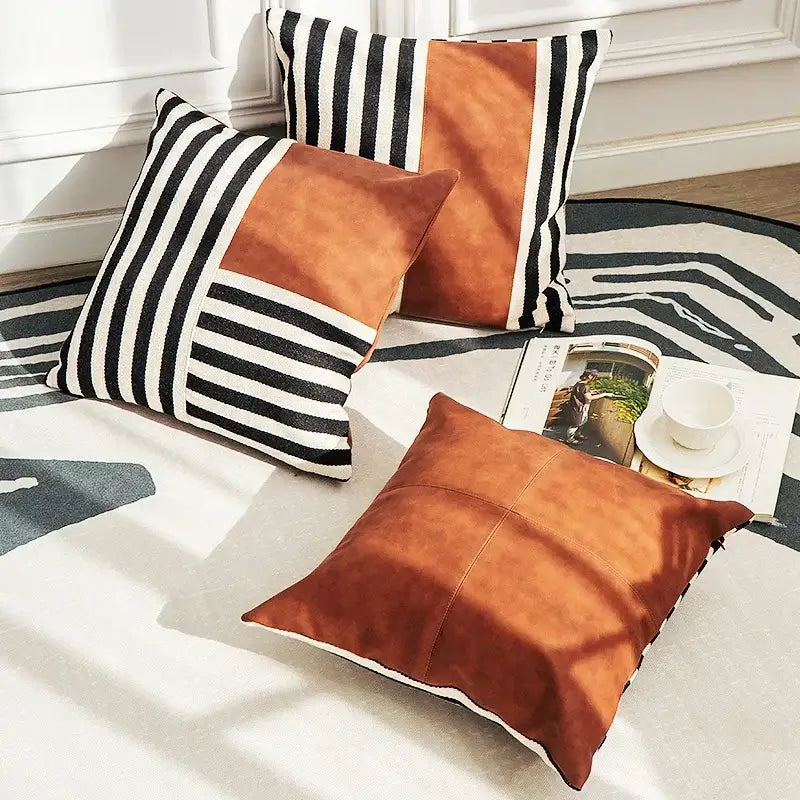 Two square pillow covers with decorbites black stripe faux leather and rust suede panels for living room decor