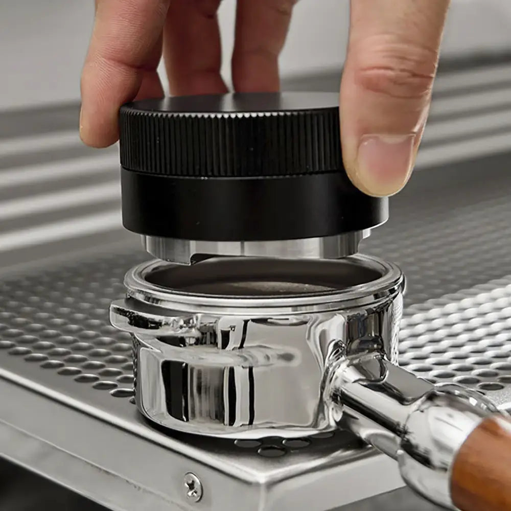 Black textured espresso tamper with metallic base pressing ground coffee in chrome portafilter decorbites espresso tamper
