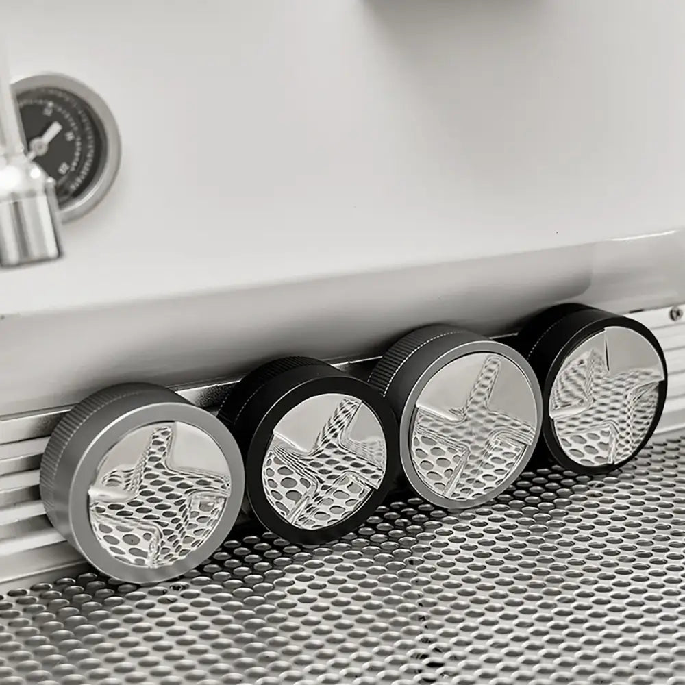 Four metallic decorbites espresso tamper knobs with black textured ridged edges and star-shaped cutouts for precise tamping