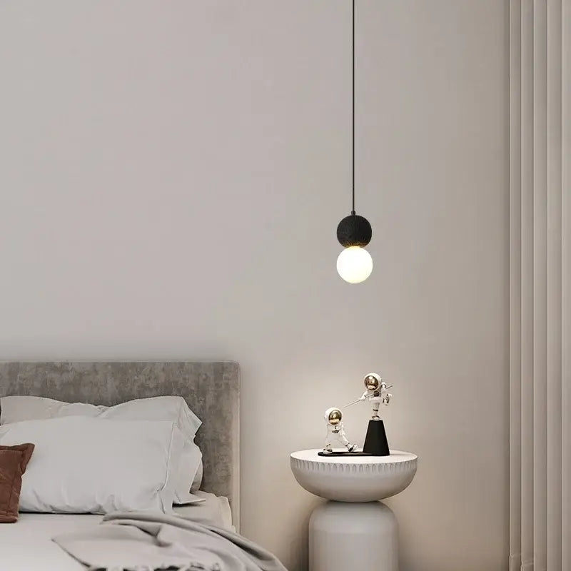 Minimalist black travertine led pendant light with a spherical lava stone globe hanging above the bedside table