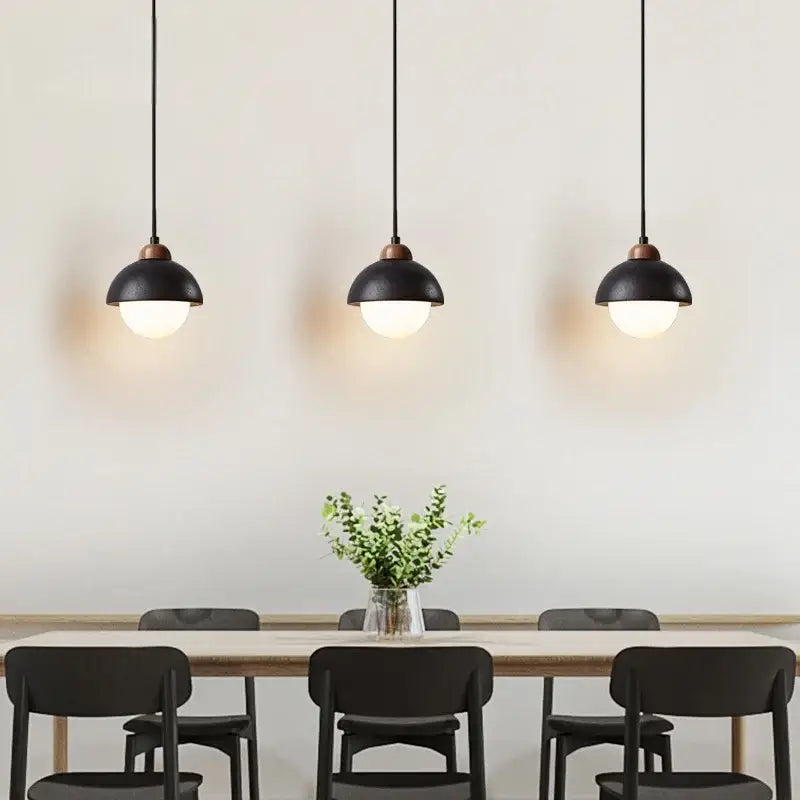 Three black travertine pendant lights with frosted glass shades hang above a dining table decorbites glass ball lamp