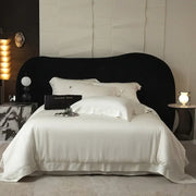 Black velvet headboard with a sleek curved design complements the lyocell eucalyptus fiber bedding set for luxury softness