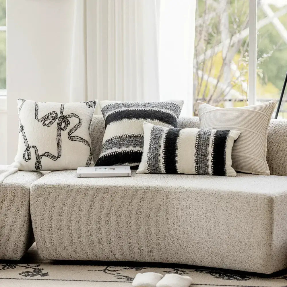 A set of four black and white abstract patterned decorbites knitted crochet cushion covers in neutral tones for living room decor