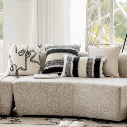 A set of four black and white abstract patterned decorbites knitted crochet cushion covers in neutral tones for living room decor