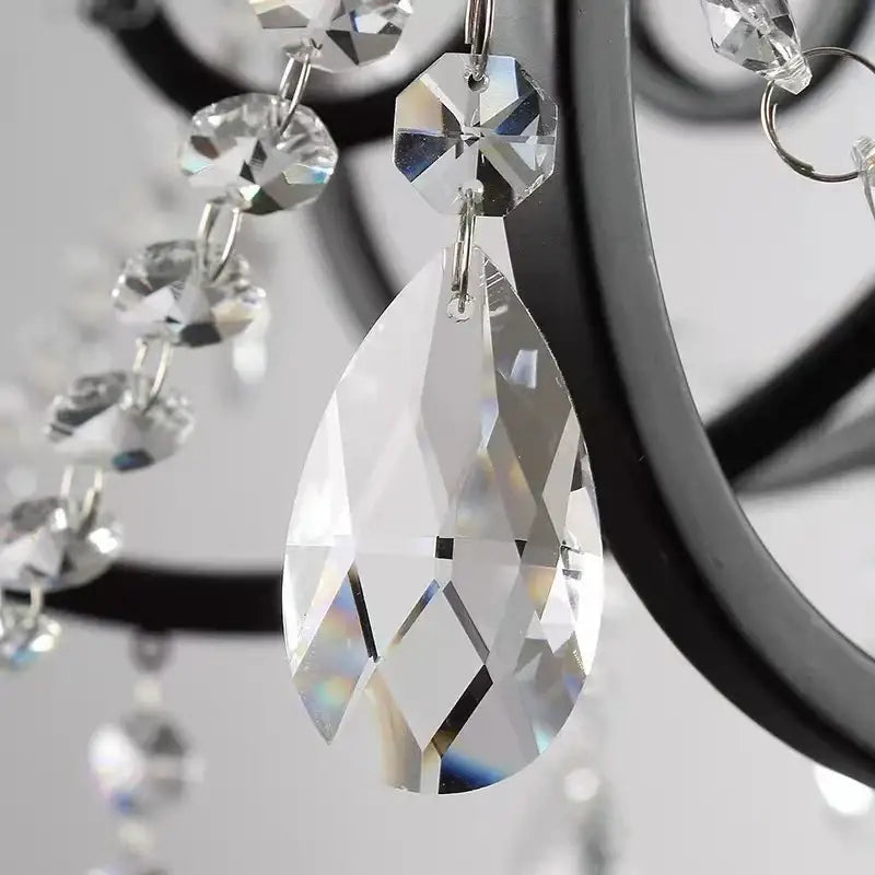 Clear faceted teardrop crystal pendant hanging from black wrought iron decorbites crystal candle chandelier