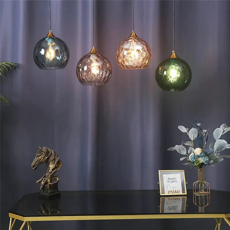 Four decorbites glass ball pendant lights with textured blue gray, amber, rose gold, and emerald green glass tops