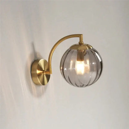 A sleek blue and brass wall lamp featuring a colored glass ball shade for bedroom lighting decorbites colored glass