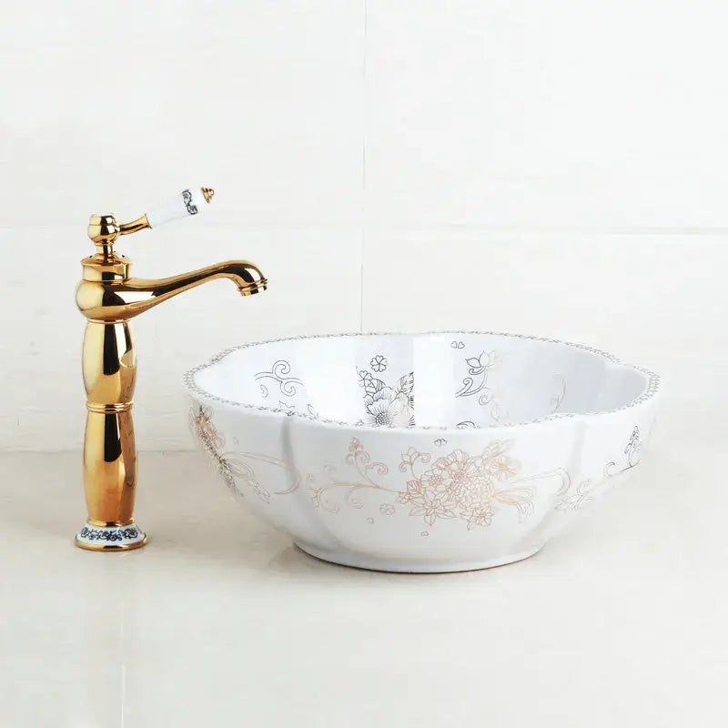 White hand painted ceramic vessel sink set with gold silver floral scrollwork and polished brass faucet with porcelain handle