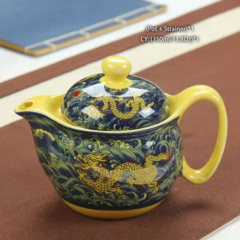 A glossy ceramic decorbites dragon teapot with yellow accents and gold dragon motifs on a deep blue tea set