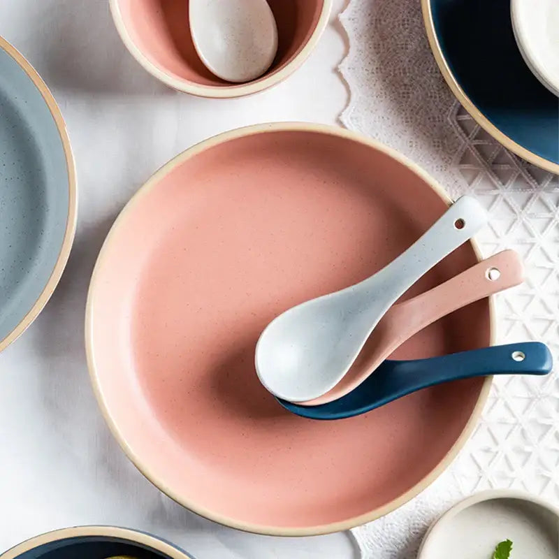 A pink ceramic morandi plate with a gold rim holding three pastel ceramic spoons for decorbites ceramic morandi dining decor