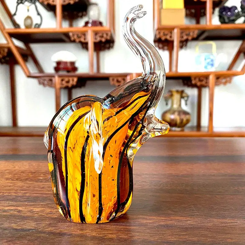A translucent amber crystal glass elephant sculpture with black and gold stripes for living room decor
