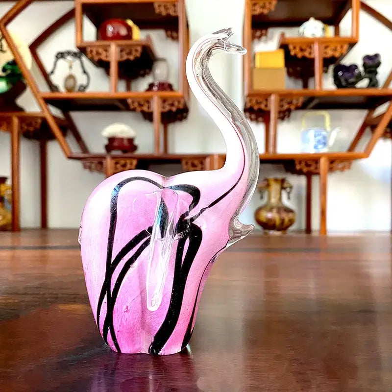 A translucent pink crystal glass elephant sculpture with black swirling patterns and clear curved trunk for living room decor