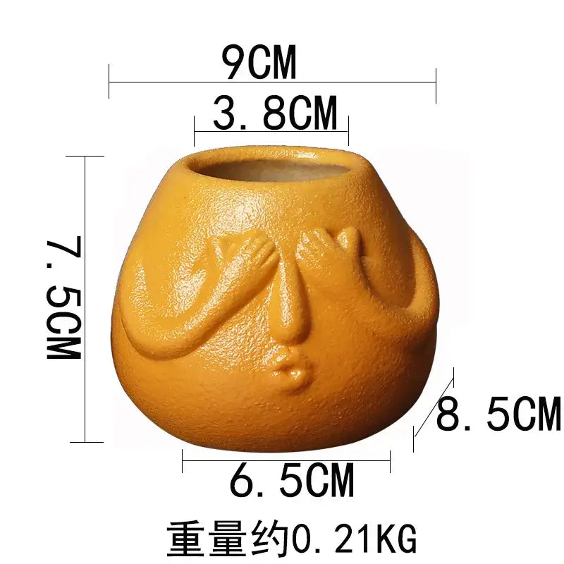A matte orange decorbites ceramic abstract planter shaped like a human face with hands covering its eyes for living room decor