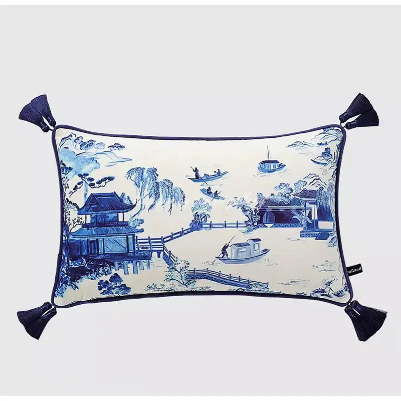 Cream-colored throw pillow case with blue and white porcelain landscape design and dark blue corner tassels for living room
