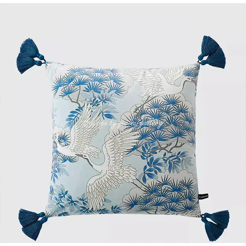 Square throw pillow case with blue and white crane and pine pattern on light gray fabric with deep blue tassels