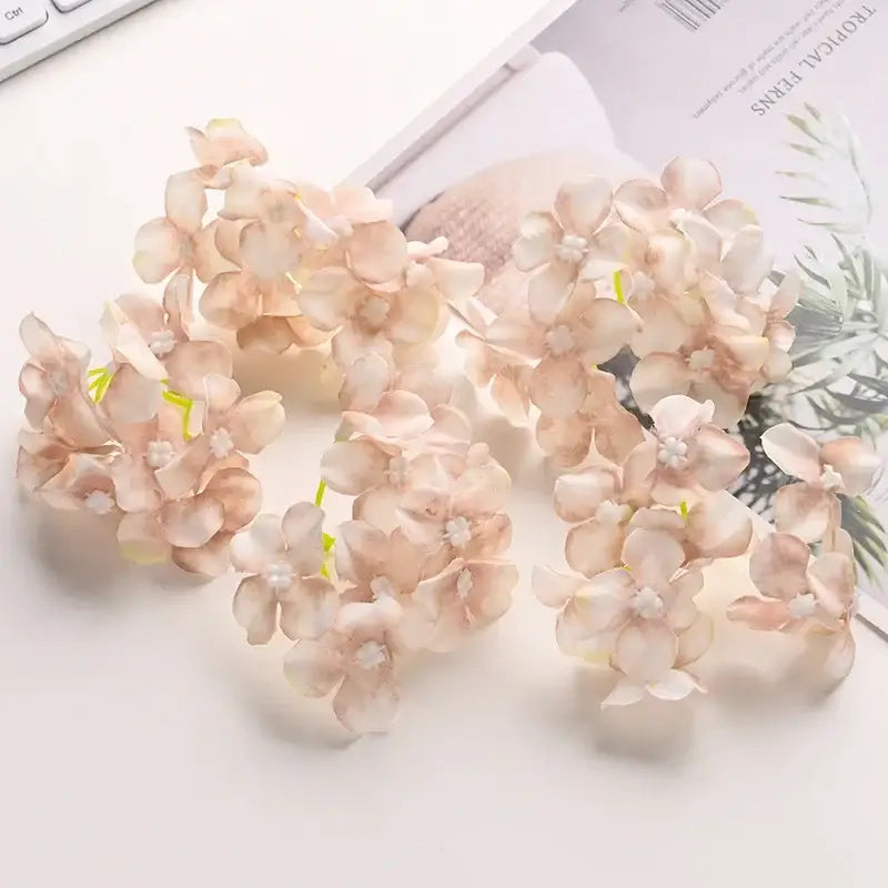 Delicate peach-colored artificial hydrangea flower clusters with soft, layered petals and tiny white centers.