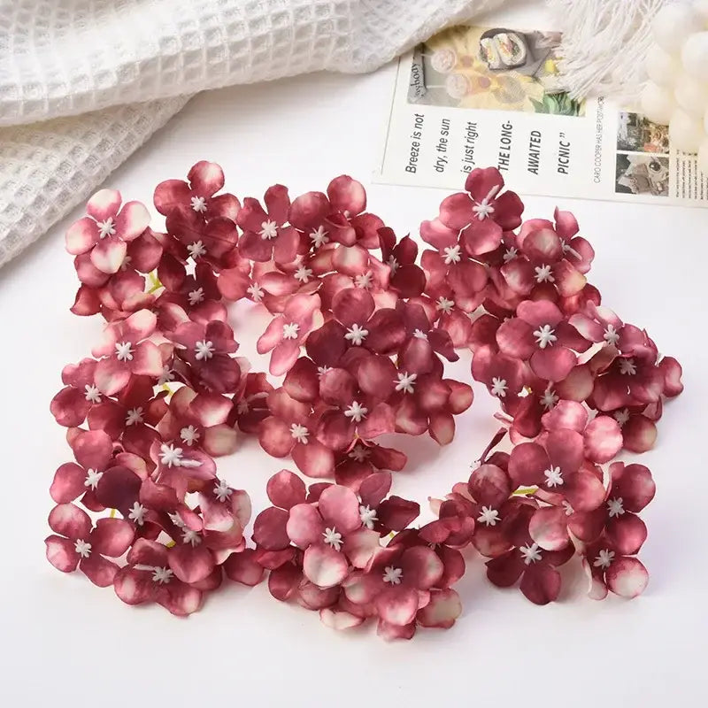 A cluster of artificial burgundy and white decorbites hydrangea flowers with delicate layered petals for wedding decor
