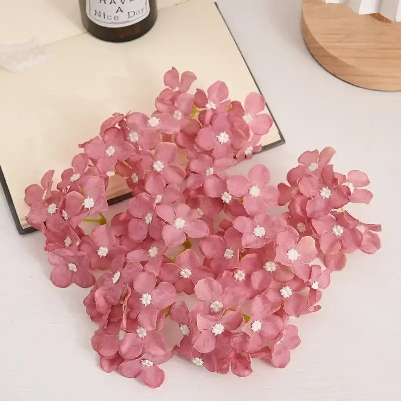 A cluster of delicate pink fabric hydrangea flowers with white centers from decorbites hydrangea flowers wedding decor set