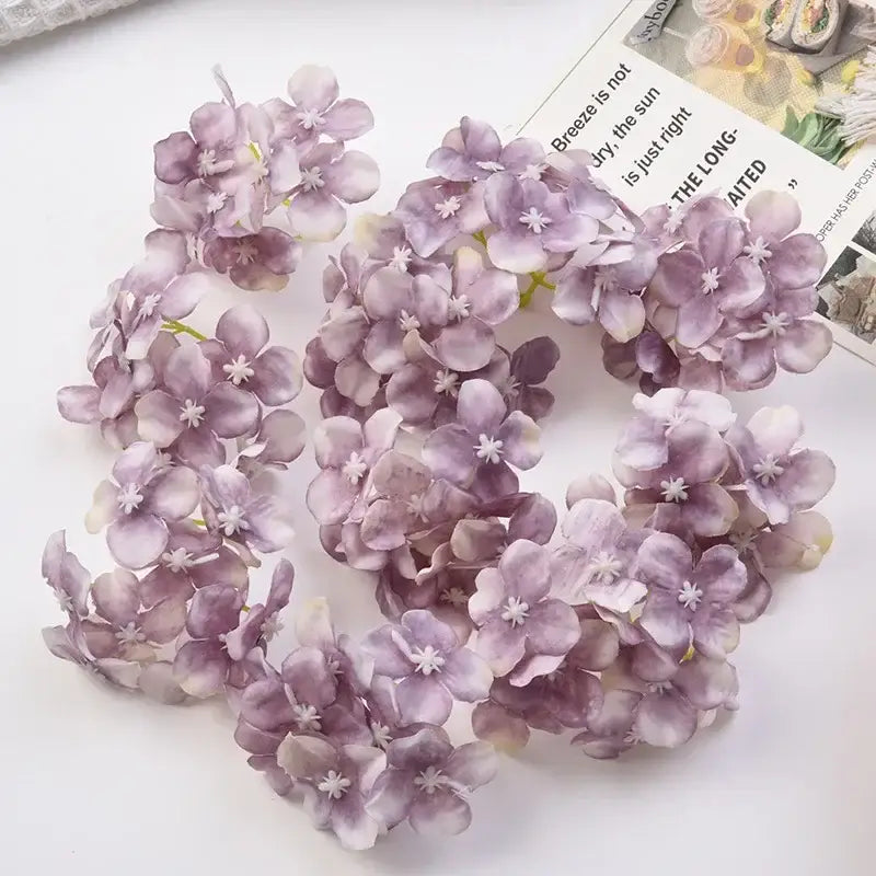 A cluster of decorbites hydrangea flowers in soft lavender and pale purple hues with white centers for wedding decor