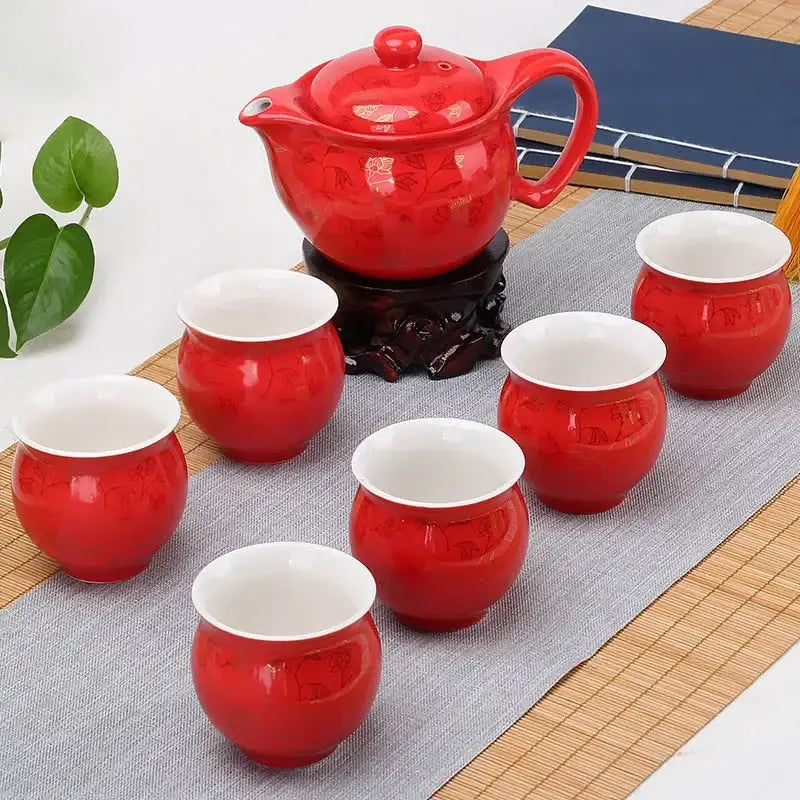 Red ceramic double ceramic teaware set with glossy finish and floral patterns featuring teapot and six cups on wooden stand
