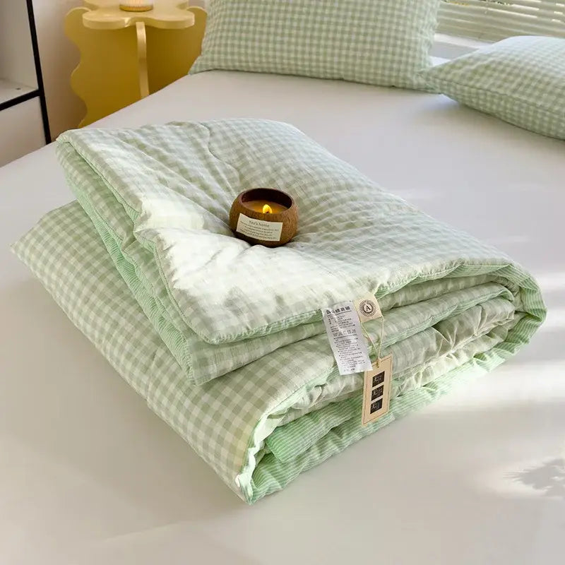 Soft mint green and white gingham cotton summer quilt with ribbed edge made from soybean fiber neatly folded on bed