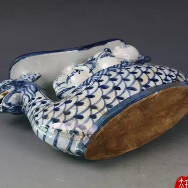 Blue and white porcelain dragon boat statue featuring a reclining figure on a stylized bird with fish scale patterns for bedroom decor
