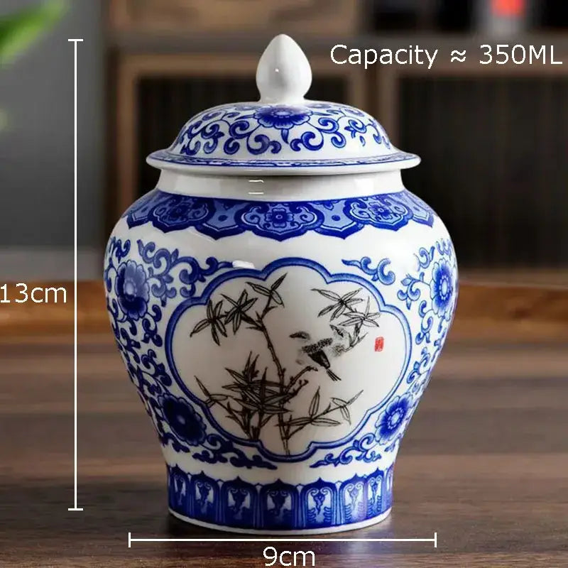 A white porcelain general jar tea canister with blue and black floral and bird design and matching lid for dining room decor