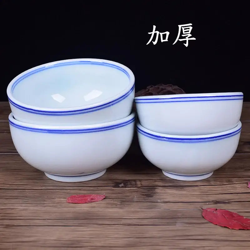 White porcelain rice bowls with delicate blue rims stacked neatly on wooden surface for dining room use
