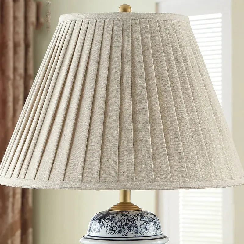 Beige pleated fabric lampshade with gold-toned finial and base on decorbites blue porcelain table lamp for living room decor