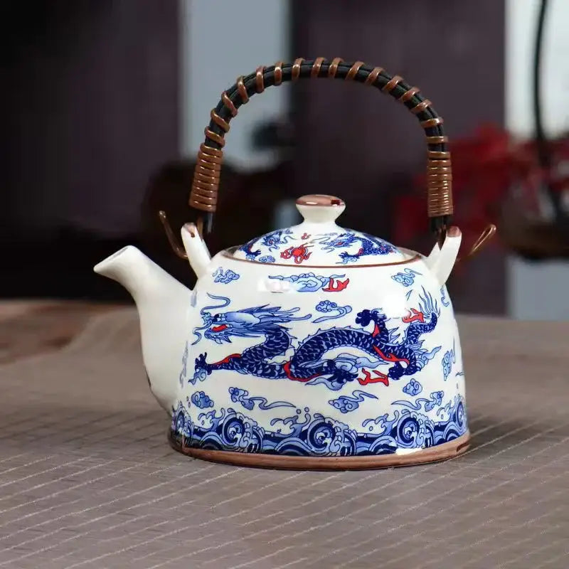 White porcelain teapot with intricate blue and red dragon motifs, woven bamboo handle, part of decorbites blue set