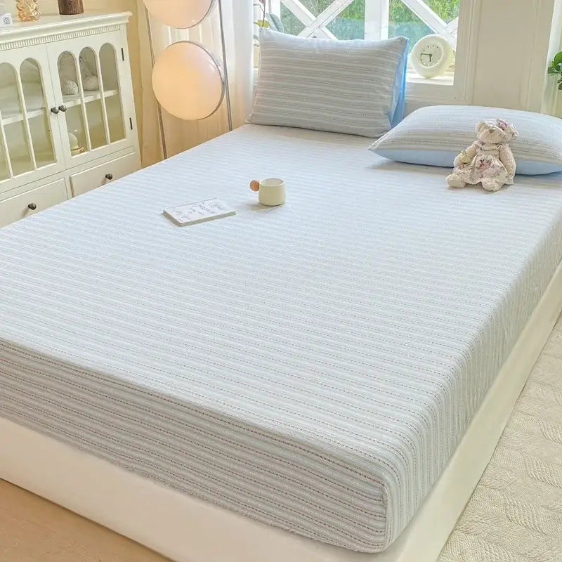 Light blue striped fitted sheet protector with subtle vertical ribbing made of soft breathable fabric for bedroom use