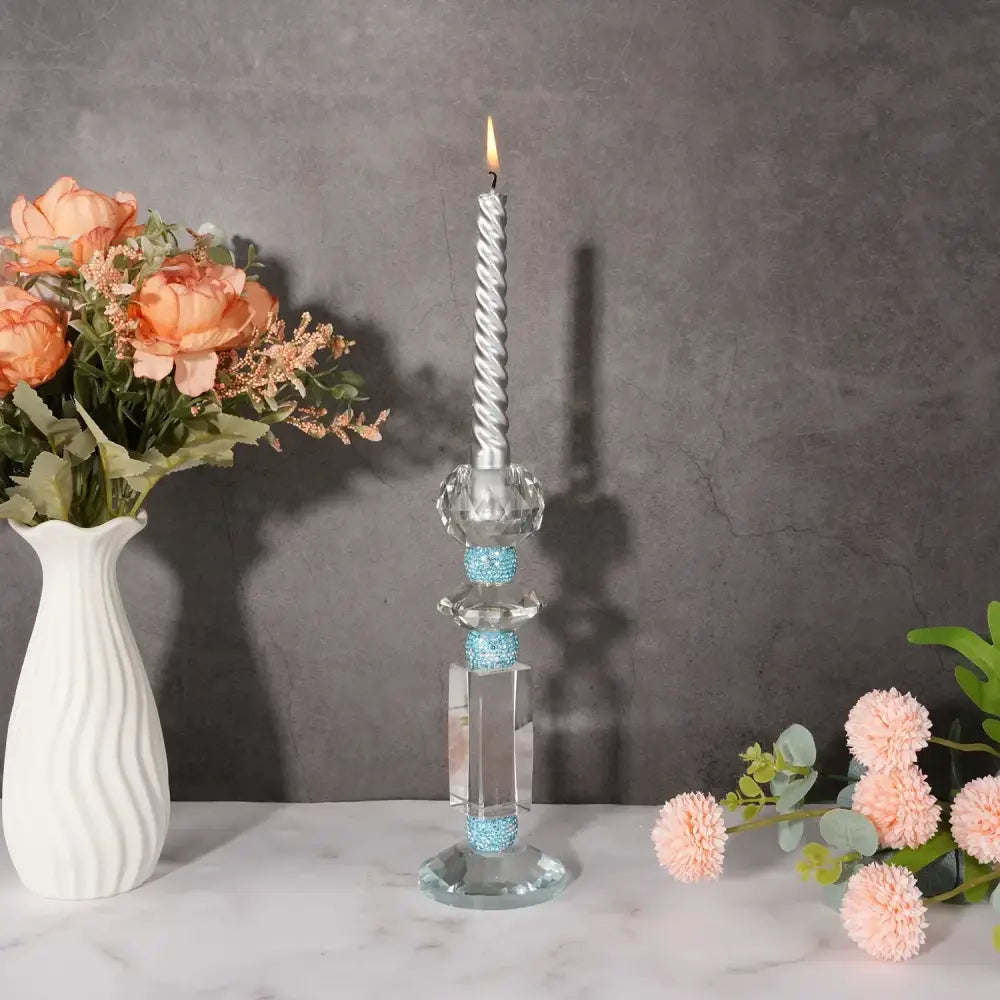 A silver twisted candle with flame in decorbites blue diamond crystal glass holder with blue beaded accents for dining room decor